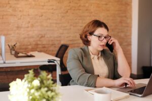 a woman talking on a phone while working on laptop
