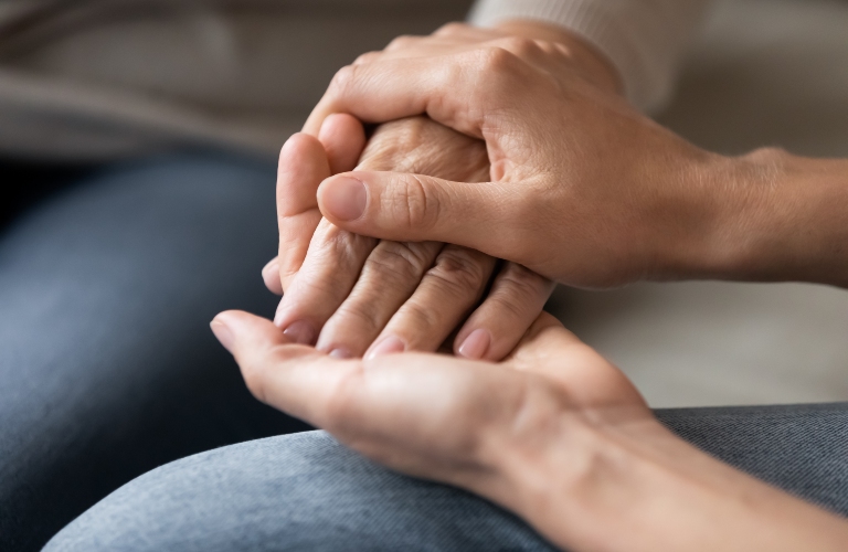 woman holds another woman's hand, giving her support