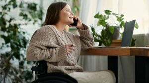 young woman with a disability sits in her wheelchair and talking on her phone