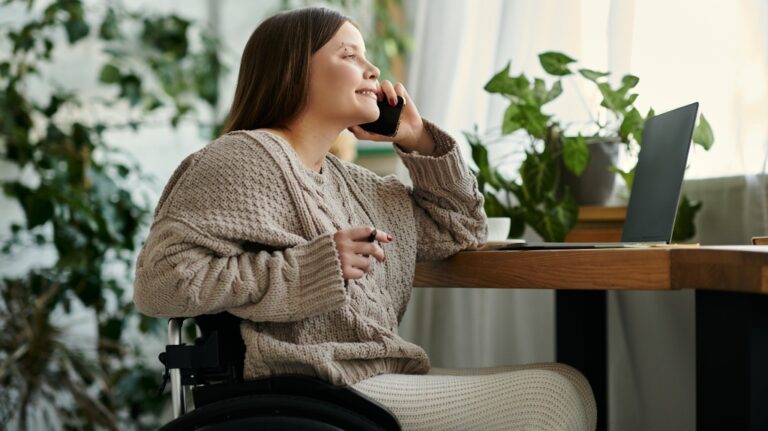 young woman with a disability sits in her wheelchair and talking on her phone
