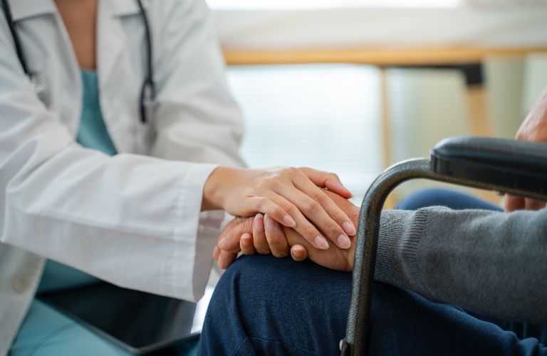 nurse holds a man in a wheelchair by the hand
