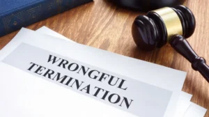 Close-up of a wooden judge's gavel next to documents titled "Wrongful Termination" on a wooden surface.