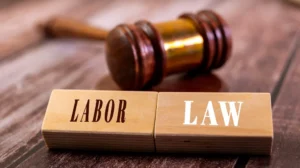 Wooden blocks with the words "LABOR" and "LAW" in front of a wooden judge's gavel.